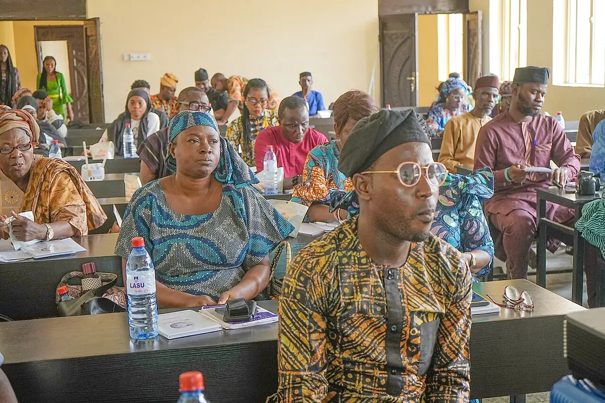 Rows of conference participants in traditional attire seated at desks in a hall
